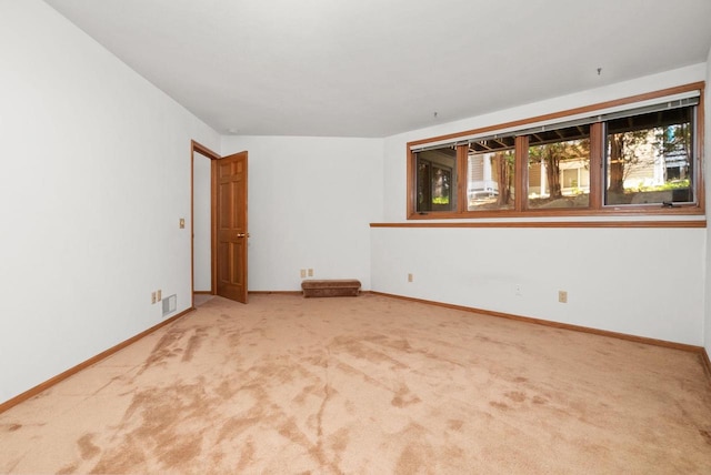 carpeted spare room with visible vents and baseboards