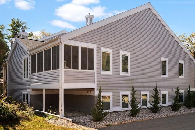 view of property exterior featuring a sunroom and a chimney