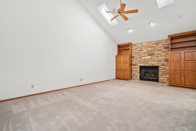 unfurnished living room with high vaulted ceiling, light colored carpet, a skylight, a fireplace, and baseboards