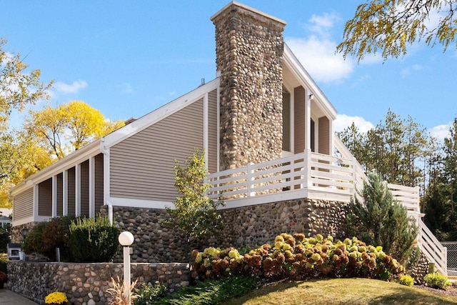 view of side of home with stone siding and a chimney