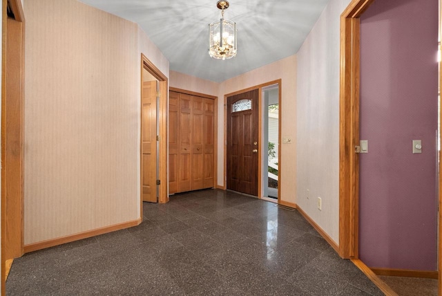 entryway with granite finish floor, baseboards, and a chandelier