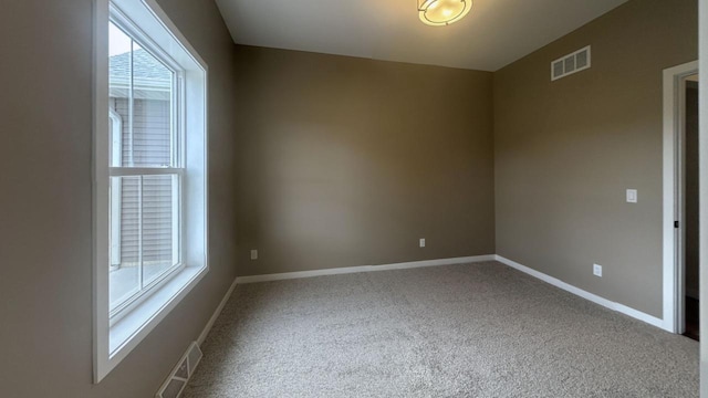 spare room featuring carpet, visible vents, and baseboards