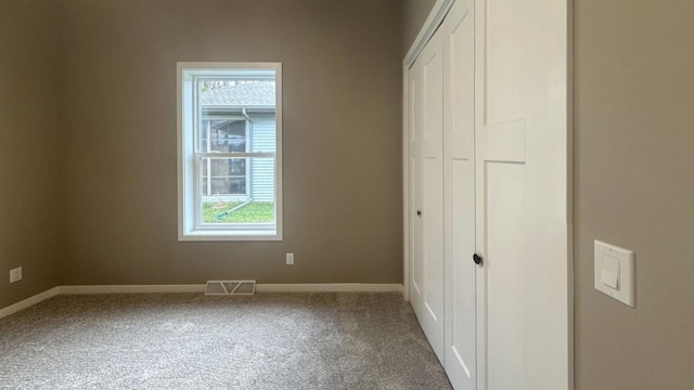 unfurnished bedroom featuring carpet, a closet, visible vents, and multiple windows