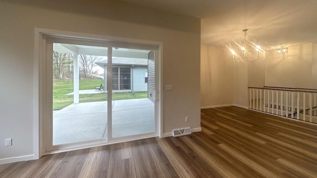 entryway featuring visible vents, a notable chandelier, baseboards, and wood finished floors