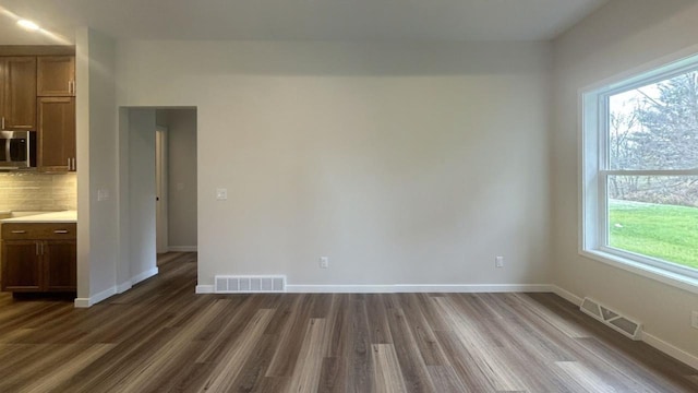 spare room featuring dark wood-type flooring, visible vents, and baseboards