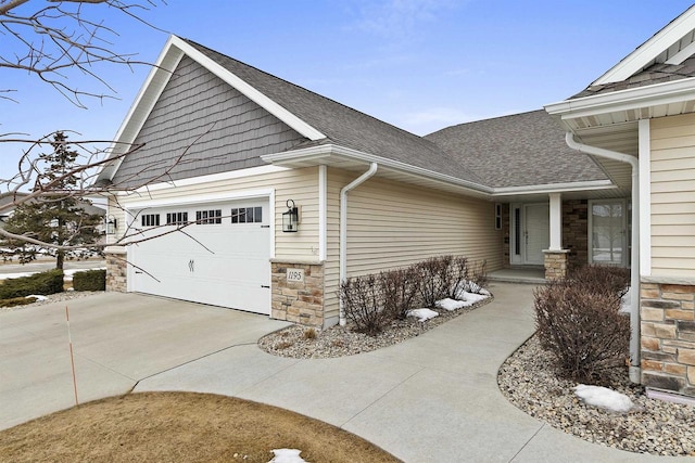 view of side of home with a garage, stone siding, roof with shingles, and concrete driveway