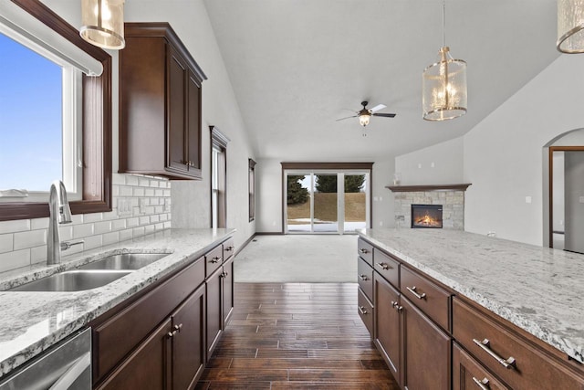 kitchen featuring decorative backsplash, vaulted ceiling, a sink, and stainless steel dishwasher