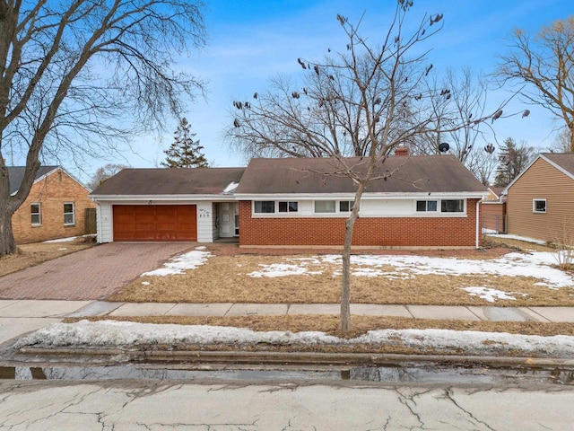 view of front of home with aphalt driveway, brick siding, a chimney, and an attached garage