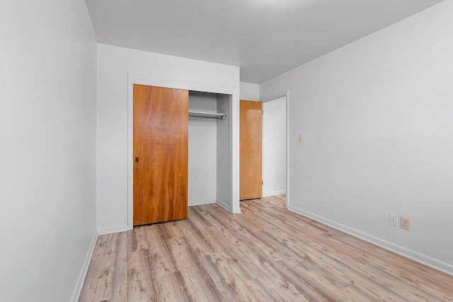 unfurnished bedroom with a closet, light wood-type flooring, and baseboards