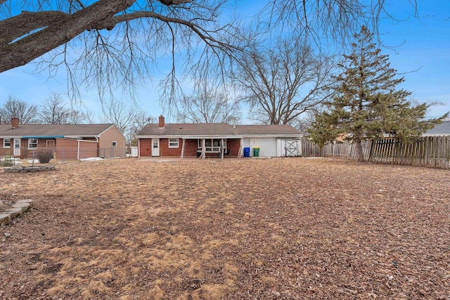 back of property featuring brick siding, a chimney, and fence private yard