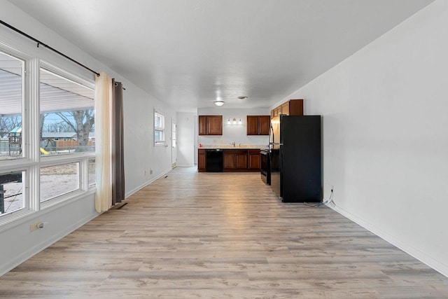 kitchen featuring light wood-type flooring, baseboards, light countertops, and black appliances