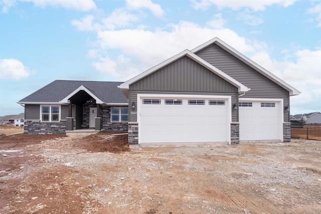 view of front of house with a garage, stone siding, and driveway