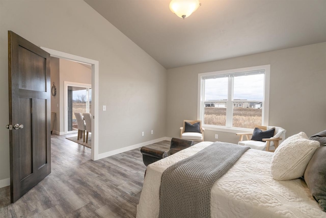 bedroom featuring lofted ceiling, baseboards, and wood finished floors