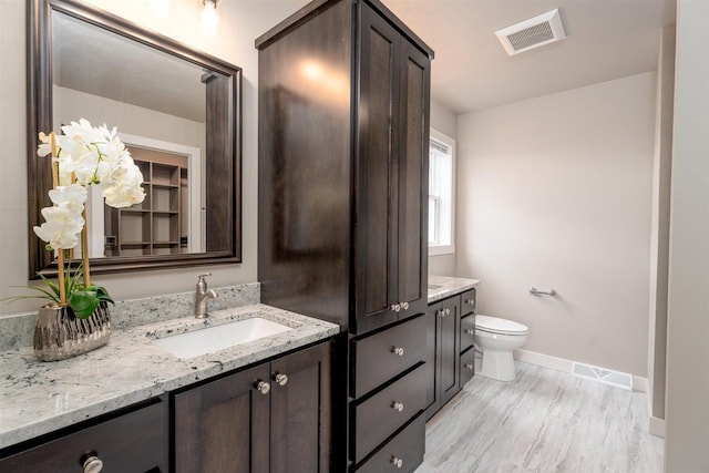 bathroom with toilet, visible vents, wood finished floors, and vanity