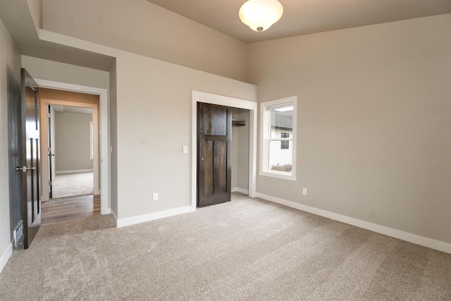 unfurnished bedroom with a closet, light colored carpet, visible vents, and baseboards