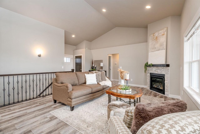 living room featuring high vaulted ceiling, light wood-type flooring, a fireplace, and recessed lighting