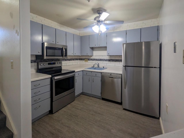 kitchen with backsplash, gray cabinets, stainless steel appliances, and a sink