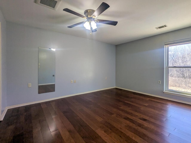 unfurnished room with dark wood-style flooring, visible vents, and baseboards