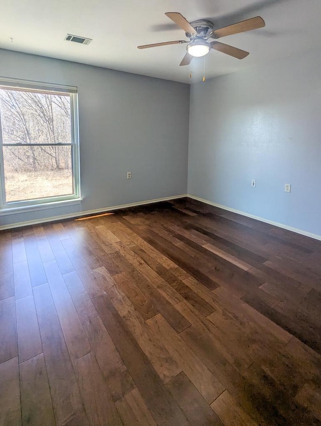 spare room with dark wood-type flooring, visible vents, baseboards, and a ceiling fan