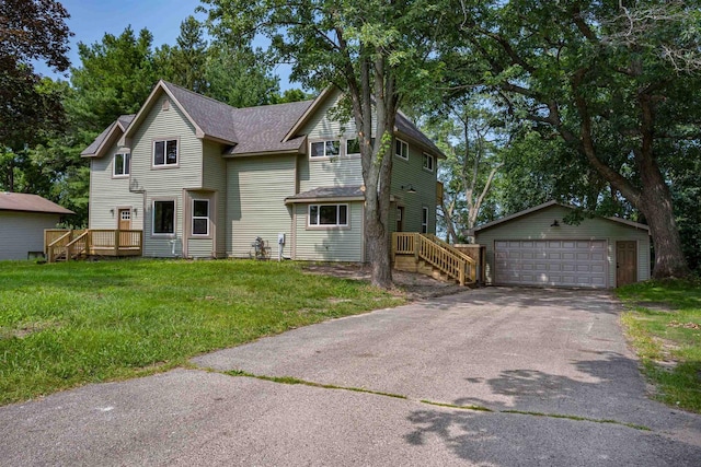 view of front of home featuring an outbuilding, a front lawn, roof with shingles, and a garage