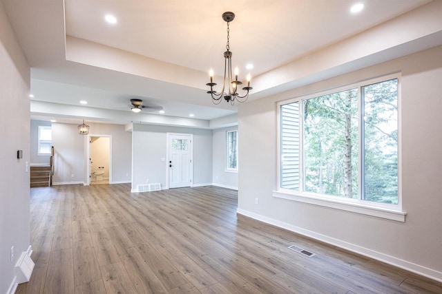 interior space featuring baseboards, visible vents, a raised ceiling, and wood finished floors