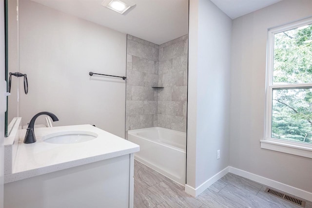 full bathroom featuring a wealth of natural light, visible vents, vanity, and baseboards