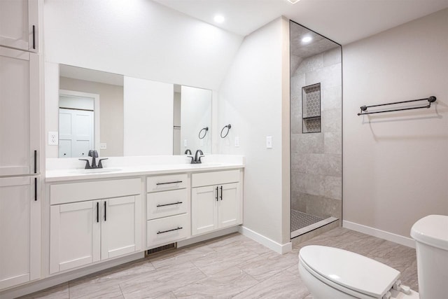 bathroom featuring a walk in shower, double vanity, a sink, and toilet