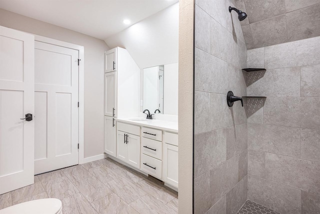 full bath with lofted ceiling, marble finish floor, tiled shower, and vanity