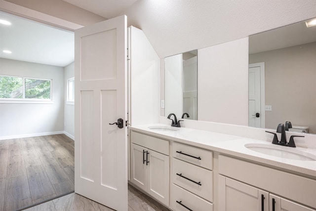 bathroom with double vanity, a sink, and baseboards