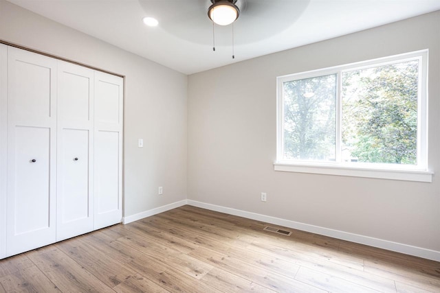 unfurnished bedroom featuring light wood-style floors, a closet, visible vents, and baseboards