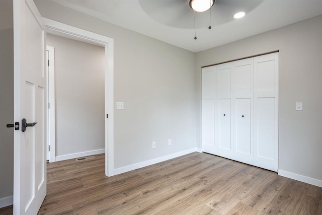 unfurnished bedroom featuring ceiling fan, a closet, light wood-type flooring, and baseboards