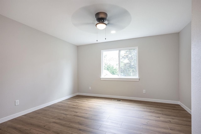 spare room with ceiling fan, wood finished floors, visible vents, and baseboards