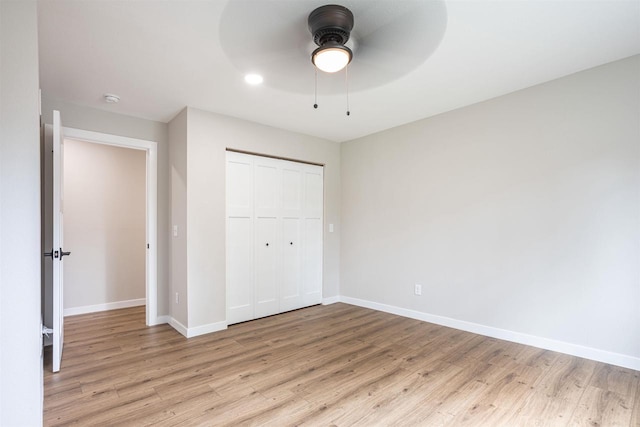 unfurnished bedroom with light wood-style flooring, baseboards, and a closet