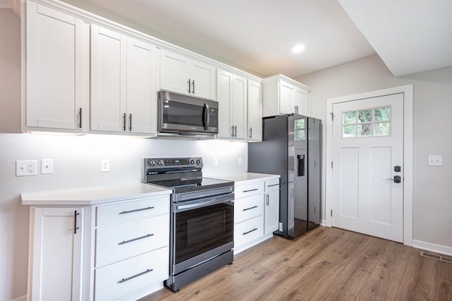 kitchen with stainless steel appliances, light countertops, visible vents, and light wood-style floors