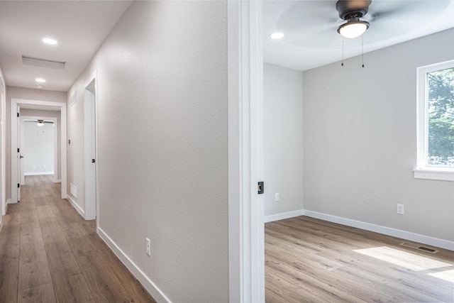 corridor with wood finished floors, visible vents, and baseboards