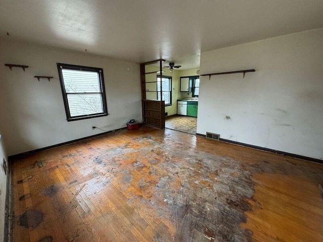 unfurnished room featuring baseboards, visible vents, and hardwood / wood-style floors