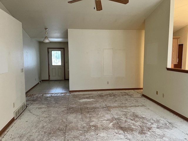 spare room with a ceiling fan, visible vents, and baseboards