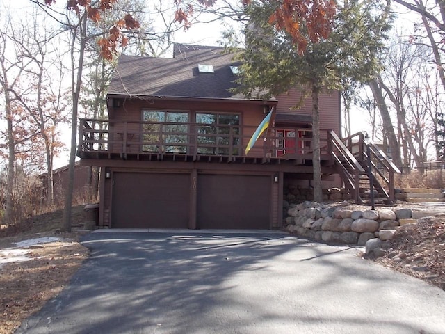 rustic home featuring stairs, aphalt driveway, a garage, and a shingled roof