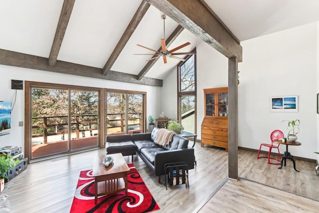 living room featuring beamed ceiling, a ceiling fan, and a wealth of natural light