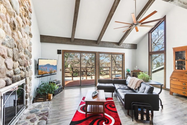 living area with ceiling fan, beam ceiling, a fireplace, wood finished floors, and high vaulted ceiling