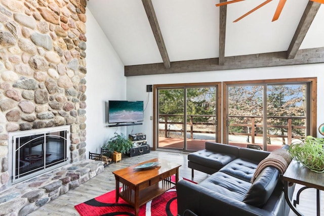 living area featuring beamed ceiling, a fireplace, ceiling fan, and wood finished floors