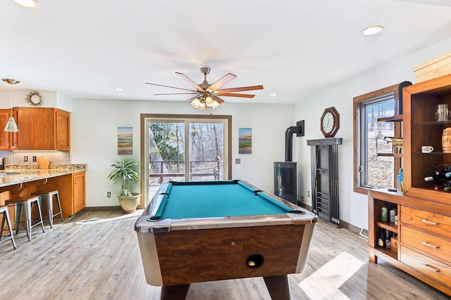 rec room featuring light wood-type flooring, a wood stove, ceiling fan, and billiards