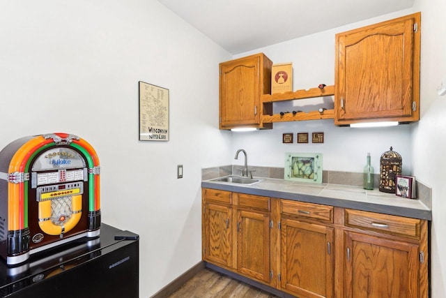 kitchen with a sink, baseboards, brown cabinets, and wood finished floors