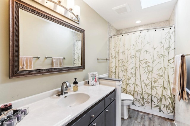 bathroom with visible vents, toilet, vanity, and wood finished floors