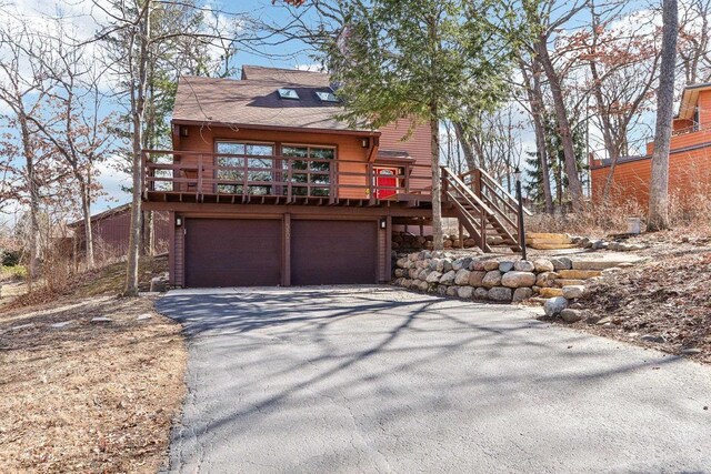 rustic home with aphalt driveway, stairway, an attached garage, and a wooden deck