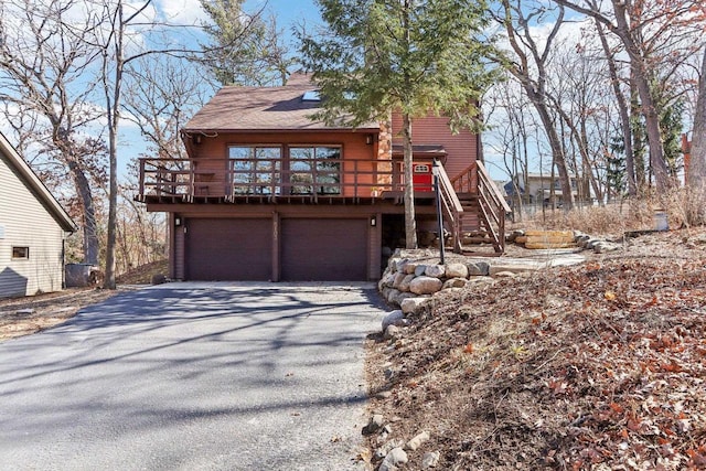 rustic home with aphalt driveway, stairway, and a garage