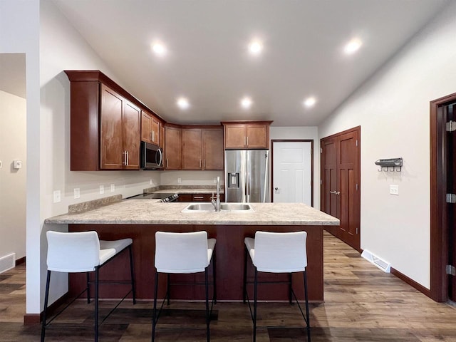 kitchen with a peninsula, stainless steel appliances, a sink, and light countertops