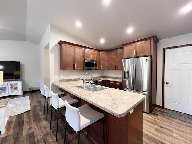 kitchen with appliances with stainless steel finishes, lofted ceiling, light countertops, and a breakfast bar