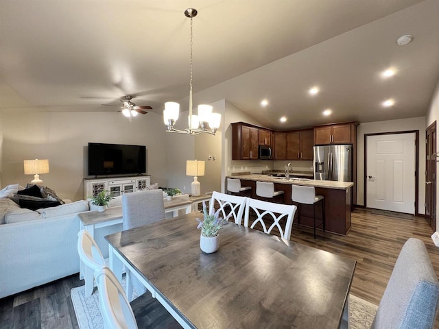 dining room with lofted ceiling, dark wood-style flooring, ceiling fan with notable chandelier, and recessed lighting