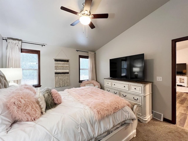 carpeted bedroom with vaulted ceiling, baseboards, visible vents, and a ceiling fan